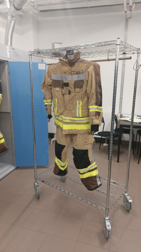 Einsatzkleidung von Rosenbauer an Aufhängung vor einem Trockenschrank